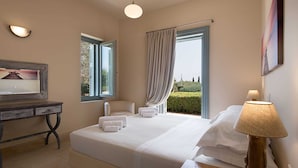 A hotel room with a large bed, a desk with a chair, a lamp, and a painting on the wall.