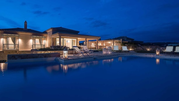A luxurious villa with a swimming pool, outdoor seating, and well-lit architecture.