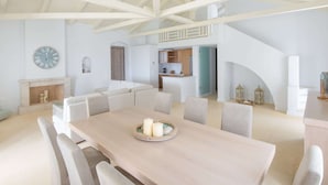 A spacious living area with a high ceiling, a dining table with candles, and a kitchen in the background. - Villa in Peloponnese With Pool (Ermionida)