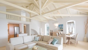 A spacious living area with a high ceiling and exposed beams, a dining area with a table and chairs, and a kitchen with wooden cabinets and a refrigerator. - Villa in Peloponnese With Pool (Ermionida)