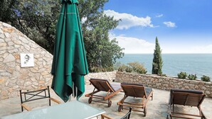 Eine Terrasse im Freien mit einer Steinmauer, einem Tisch und Lounge-Stühlen.