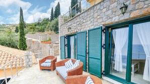 A stone building with a terrace featuring wicker furniture and a view of the sea. - Villa in Pera Melana Near Kissakas Beach (South Kynouria)