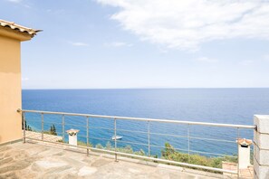 Enjoy breathtaking sea views from this balcony with a stone floor and metal railing.