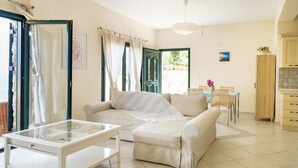 Un salon comprenant un canapé, une table basse avec un plateau en verre et un coin repas avec une table et des chaises.