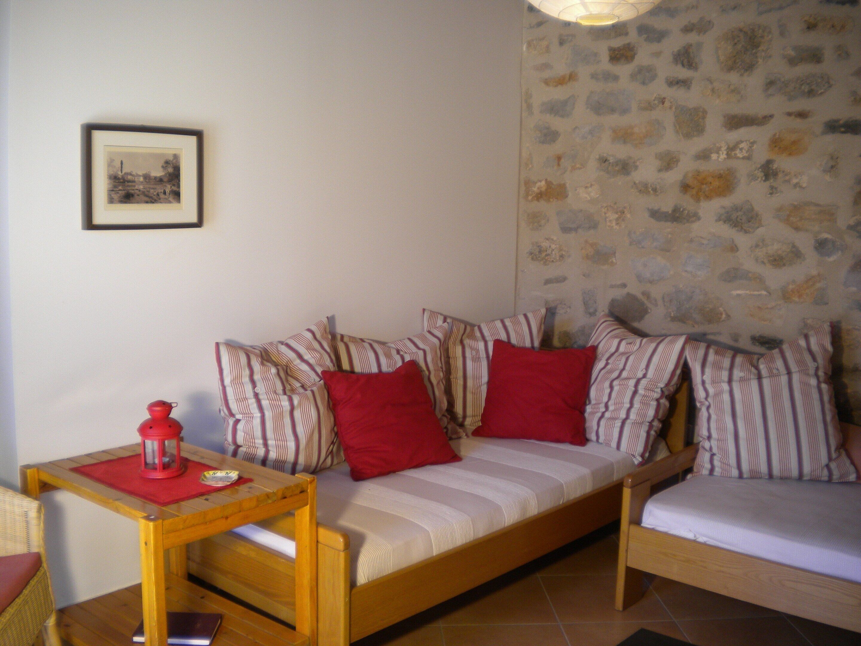A cozy room with a striped sofa, a small wooden table with a red lantern, and a stone-patterned wall.