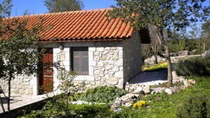A stone house with a tiled roof, a wooden door, and a window. - Chalet in Leonidio Near Mount Parnon (South Kynouria)