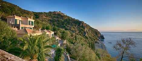 A coastal property with a stone pathway leading to a house with multiple rooms and a balcony.