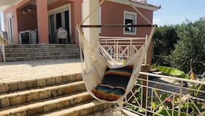 A hammock hanging over stone steps leading to a pink building with a white railing and a view of banana plants. - Luxurious Villa in Peloponnese (Pylos-Nestoras)