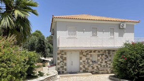 A two-story building with a stone facade, a tiled roof, and a small balcony. - Luxurious Villa in Peloponnese (Pylos-Nestoras)