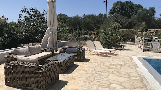 A stone patio with wicker furniture, including sofas and lounge chairs, near a swimming pool. - Luxurious Villa in Peloponnese (Pylos-Nestoras)