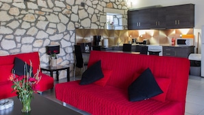 A modern living room with a red sofa and a stone wall.
