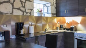 Eine moderne Küche mit Steinwand, einer Kaffeemaschine, einem Toaster und einem Spülbecken.