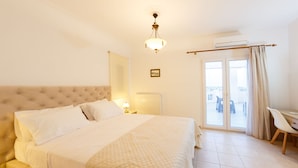 Una camera da letto con un letto grande, un comodino con una lampada, una sedia e vista sull'esterno tramite una porta scorrevole.