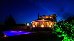 Una casa a due piani con un patio circolare e una piscina.