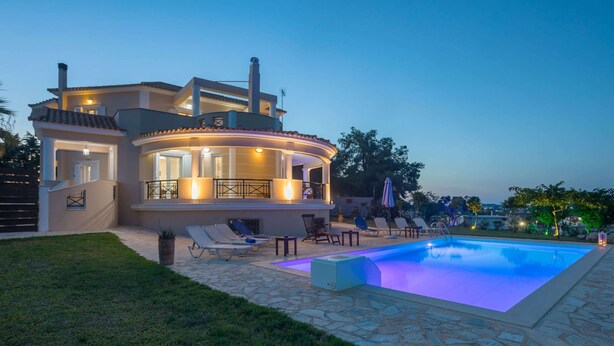 Una casa moderna con piscina, area salotto esterna e patio ben illuminato.