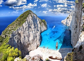 Un paisaje costero con una playa angosta, acantilados rocosos y aguas azul turquesa.