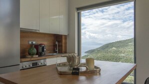 A modern kitchen with a large window offering a scenic view of a coastal landscape. - Villa in Sivota With Private Pool & Beaches (Lefkada)