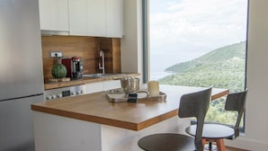 A modern kitchen with a large island, wooden countertops, and a view of a mountainous landscape. - Villa in Sivota With Private Pool & Beaches (Lefkada)