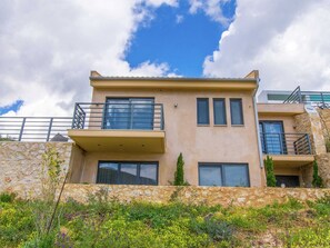 A two-story building with a stone facade, multiple balconies, and large windows. - Villa in Sivota With Sea View & Pool (Lefkada)