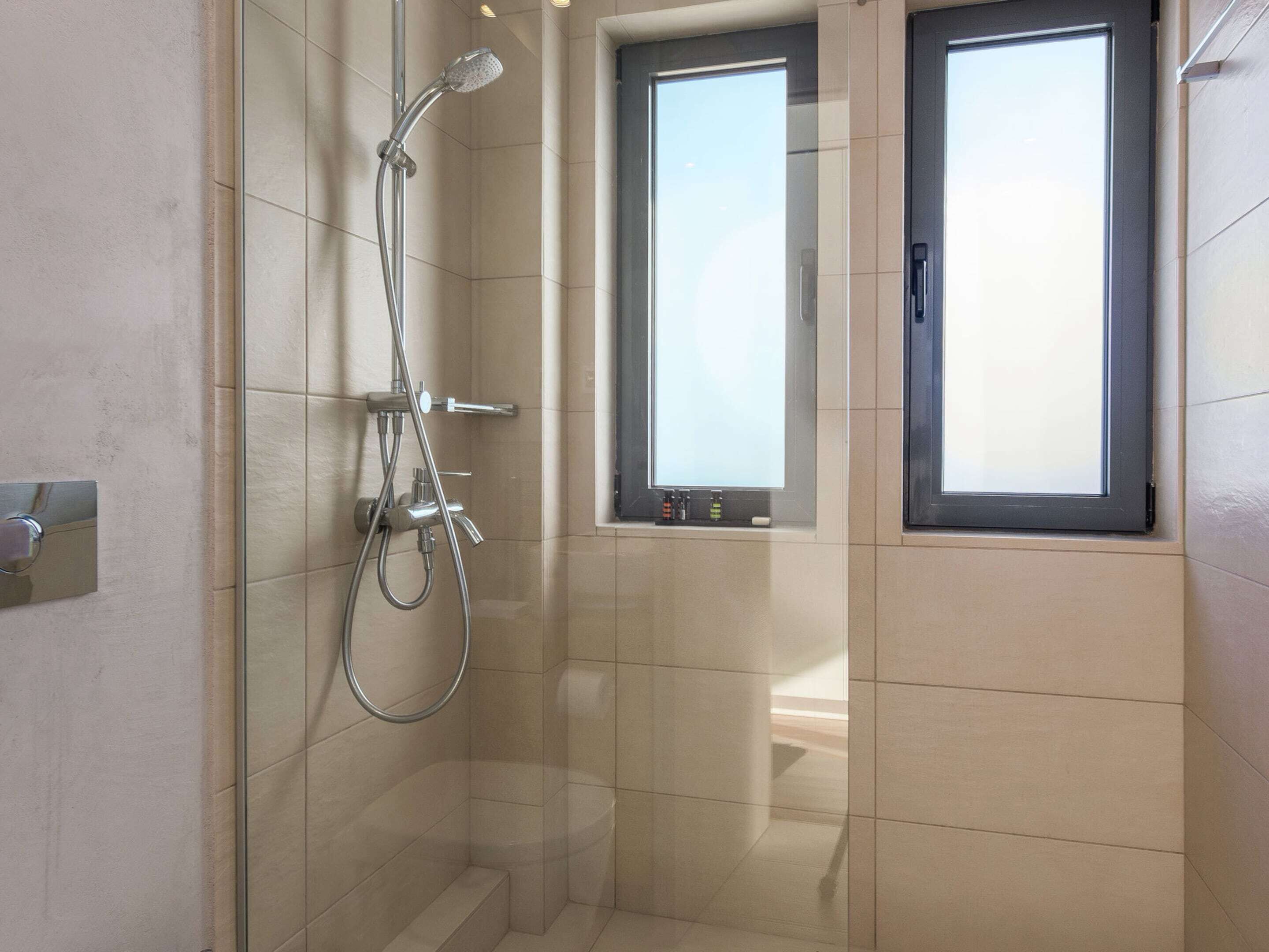 Un baño moderno con ducha de vidrio, una ventana y una bañera.