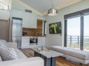 A modern kitchen with a Bosch refrigerator, a coffee maker, and a wooden countertop. There is a dining table with a tray and a glass. - Villa in Sivota With Sea View & Pool (Lefkada)
