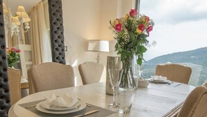Tavola imbandita per quattro, con un vaso di fiori, una lampada e vista su un paesaggio montuoso.