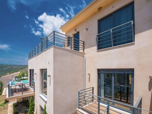 Una casa moderna de dos pisos con balcón, ventanas amplias y zona de piscina.