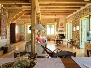 Cozy seating area with a sofa and chairs surrounds a dining table, complemented by a fireplace.