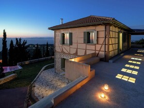 Enjoy a panoramic view of the surrounding landscape and a body of water from this hillside villa's spacious patio.