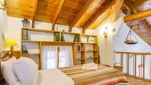 Um quarto aconchegante com uma cama, uma estante de madeira e um pendente.