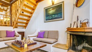 Uma sala de estar aconchegante com uma escada de madeira, lareira e um tabuleiro de xadrez sobre uma mesa.