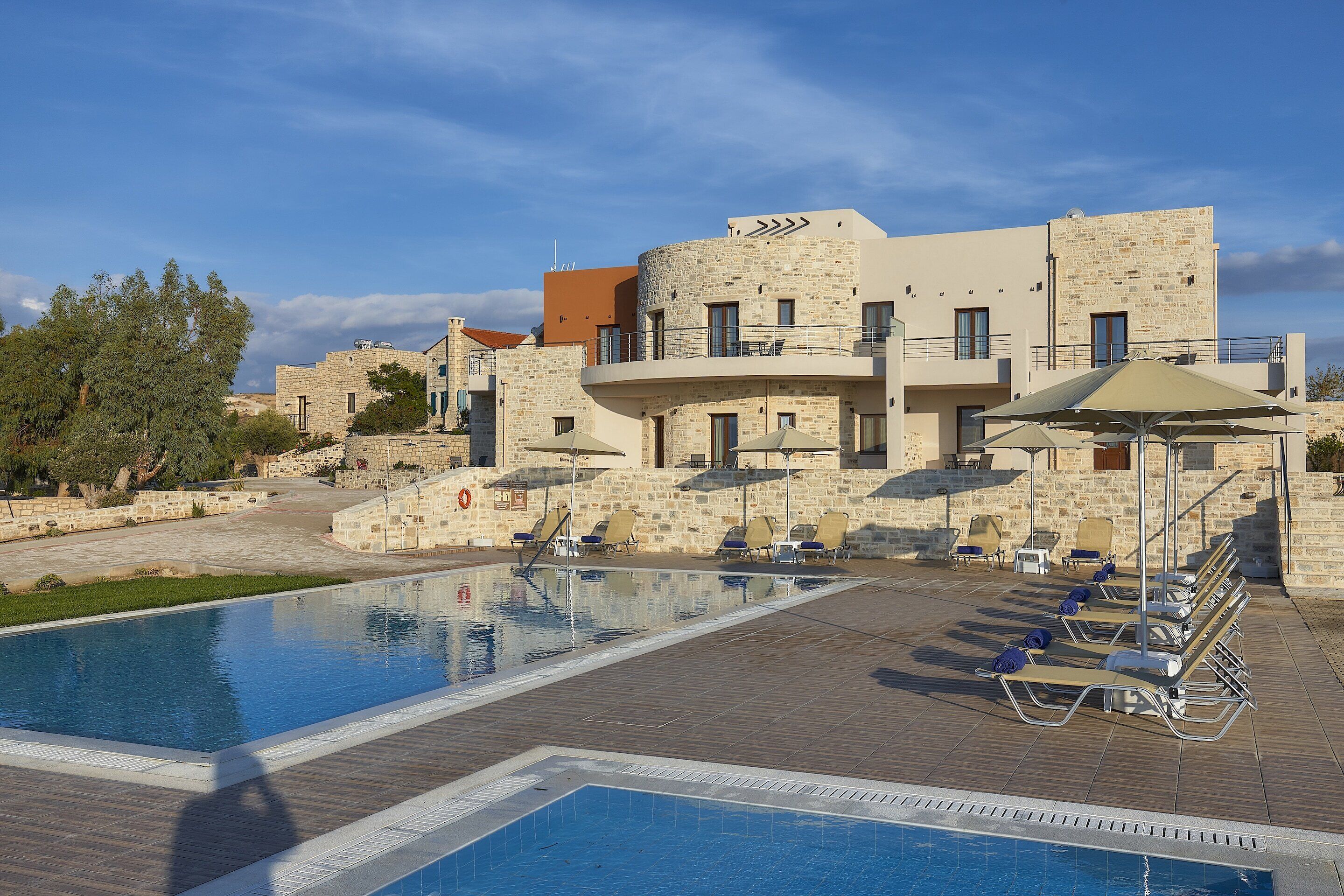 A pool area with lounge chairs and a stone building in the background.