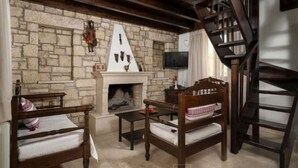 Una habitación acogedora con pared de piedra, chimenea, muebles de madera y una escalera.