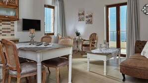 A spacious living area with a dining table, chairs, a sofa, and a balcony with a view. - New Beautiful Complex With Villa's and App, Big Pool, Stunning Views, SW Crete (Faistos)