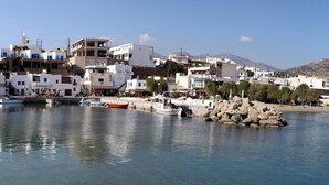 Une ville côtière avec des bâtiments le long du front de mer, des bateaux amarrés et un promontoire rocheux.