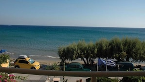Une vue sur la côte, avec un ciel dégagé, une plage et des voitures garées.