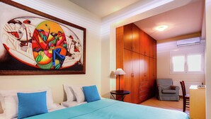 A bedroom with a bed, a painting, a wardrobe, a chair, and a table.