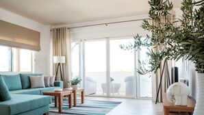 A modern living room with a teal sofa, a wooden coffee table, and a striped rug.