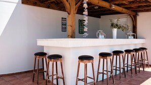 An outdoor bar area with wooden stools and a white counter.