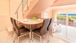 A modern dining area with a round table, four chairs, and a staircase. - Modern Villa With Heated Swimming Pool in Georgioupoli Greece (Apokoronas)