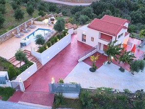A modern villa with a swimming pool, outdoor seating, and a red-tiled roof.