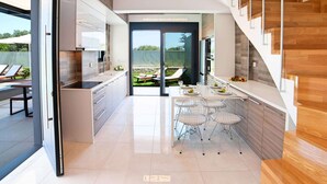 A modern kitchen with a dining area, a staircase, and a view of the outdoors. - 2 new Villas With Heated Pool, Rent Separately or Together at Kournas Lake (Apokoronas)