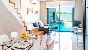 A modern living room with a glass dining table, white sofas, a staircase, and a view of a swimming pool. - 2 New Villas Next Each Other, Pool, Rent Separately or Together at Kournas Lake (Apokoronas)