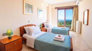 A hotel room with two beds, a nightstand, a lamp, a window with a view, and a ceiling light. - 2 Villas Next to Each Other with Pool & Sea View (Apokoronas)