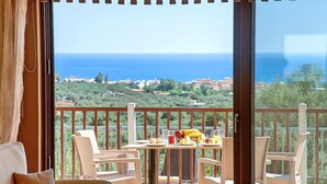 A balcony with wicker furniture, a table with fruits and glasses, and a view of the sea and landscape. - 2 Villas Next to Each Other with Pool & Sea View (Apokoronas)