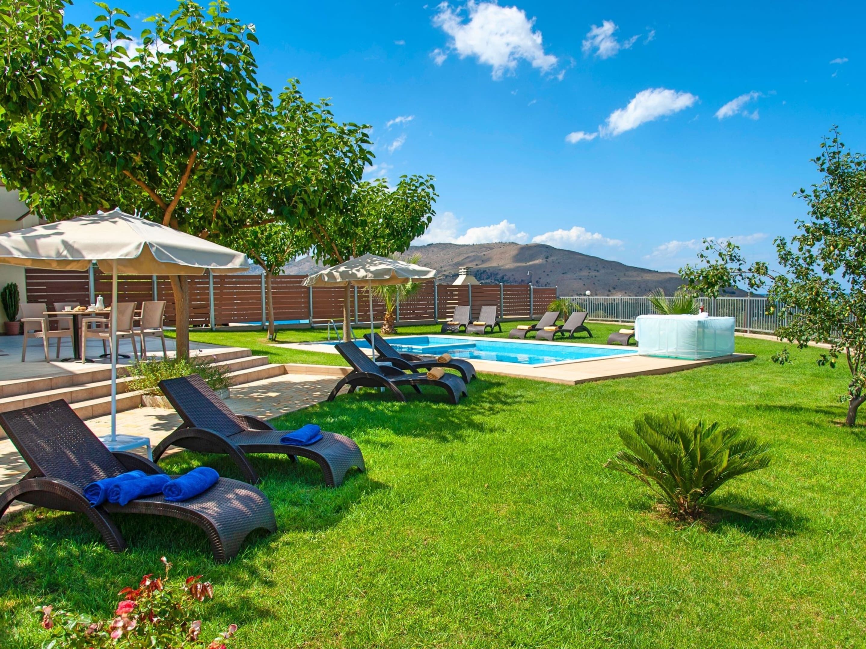 Un espace piscine avec des chaises longues, un jacuzzi et une vue sur les montagnes.