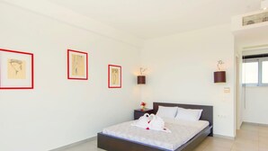 A modern bedroom with a large bed, white walls, and three framed artworks. - Sparkling Villa in Acrotiri with Private Pool near Sea Beach (Chania)