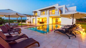 A modern two-story house with a swimming pool, outdoor seating, and a well-lit patio area. - Sparkling Villa in Acrotiri with Private Pool near Sea Beach (Chania)