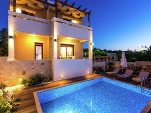 A modern villa with a swimming pool, outdoor seating, and a stone facade. - Villa with Private Pool near Sea & Arkadi Monastery on NW Coast (Rethymno)