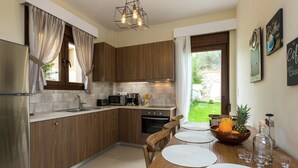 Eine moderne Küche mit Holzausstattung, einem Edelstahlkühlschrank, einer Mikrowelle und einer Essecke mit Tisch für zwei Personen.